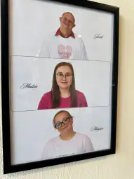 Trzy osoby w białych koszulkach, uśmiechnięte, na jasnym tle.