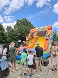 Dzieci bawią się na zjeżdżalni dmuchanej w parku.