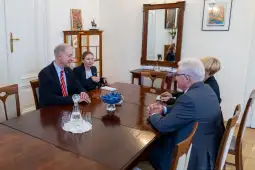 Spotkanie czterech osób przy stole w eleganckim wnętrzu.