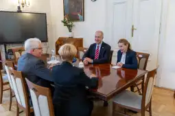 Spotkanie czterech osób przy stole w eleganckim wnętrzu.