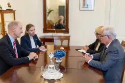 Spotkanie czterech osób przy stole, dyskusja w formalnym otoczeniu.