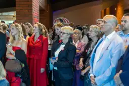 Grupa ludzi w eleganckich strojach, niektórzy z przypinkami w kształcie serca.