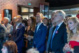 Grupa ludzi w eleganckich strojach, skupionych na wydarzeniu.