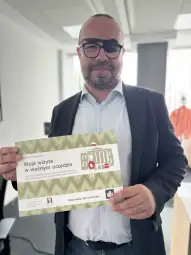 Mężczyzna trzyma certyfikat dotyczący wizyty w urzędzie.