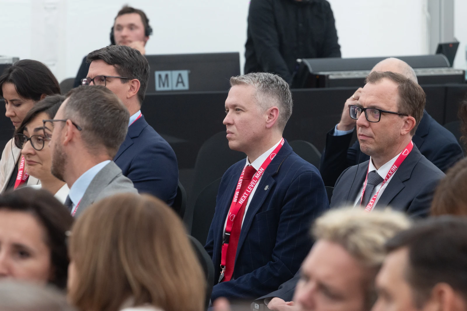 Grupa osób siedzących na konferencji, niektórzy w garniturach, z identyfikatorami na szyi.  Autor: Bogusław Świerzowski