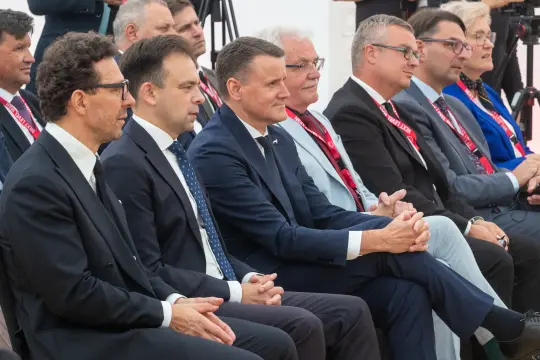 Grupa mężczyzn w garniturach siedzących w rzędzie podczas wydarzenia.