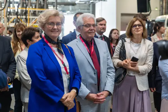 Grupa osób w formalnych strojach, uczestniczących w wydarzeniu lub konferencji.