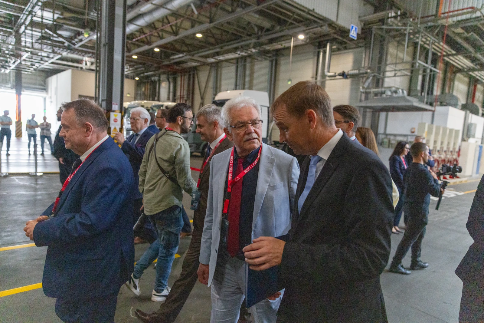 Grupa mężczyzn w garniturach rozmawia w hali przemysłowej.  Autor: Bogusław Świerzowski