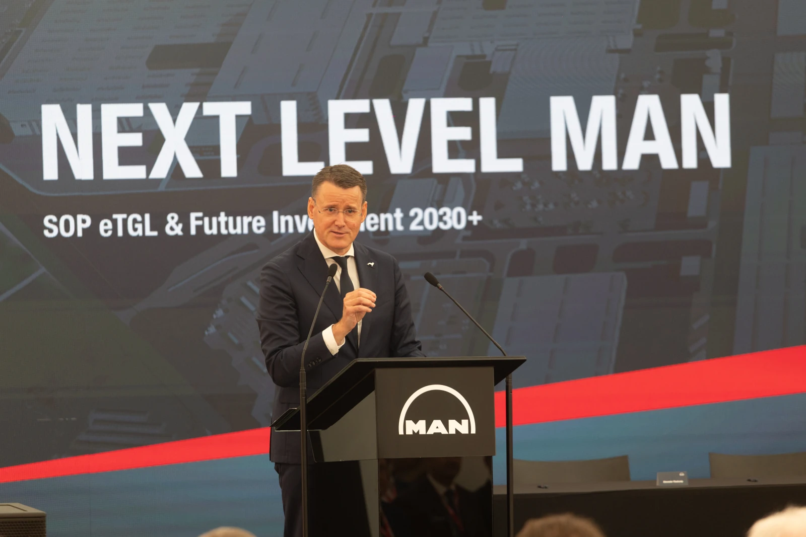 Mężczyzna przemawia na konferencji, w tle logo MAN i hasło Next Level MAN.  Autor: Bogusław Świerzowski