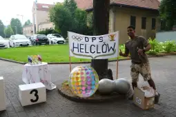 Mężczyzna z uśmiechem stoi obok baneru z napisem DPS Helcłów oraz kolorowymi dekoracjami.