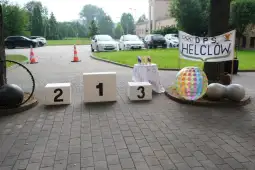 Miejsce z podium, dekoracjami i banerem z napisem DPS HELCŁÓW.