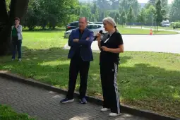 Mężczyzna w garniturze i kobieta w sportowym stroju rozmawiają na świeżym powietrzu.