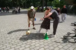 Osoby starsze grają w piłkę nożną na świeżym powietrzu, korzystając z zielonych stożków.