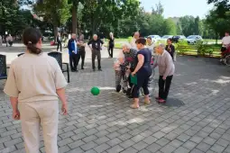 Grupa osób starszych bawi się w grę z piłką na świeżym powietrzu.