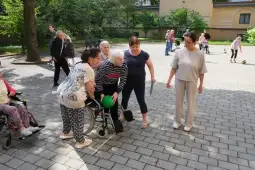 Grupa osób starszych uczestniczy w aktywności na świeżym powietrzu, wspierając się nawzajem.