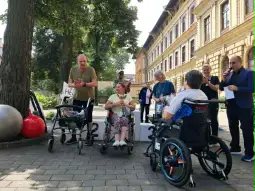 Osoby na wózkach inwalidzkich uczestniczą w wydarzeniu na świeżym powietrzu.