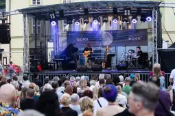 Koncert na świeżym powietrzu z zespołem grającym na scenie przed tłumem ludzi.