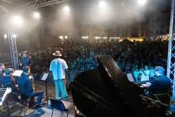 Występ muzyczny na dużej scenie przed tłumem ludzi.
