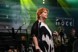 Kobieta z mikrofonem na scenie podczas koncertu jazzowego.