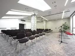 Pusta sala konferencyjna z rzędem krzeseł i podium.