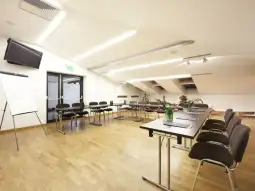 Nowoczesna sala konferencyjna z dużym stołem, krzesłami i sprzętem multimedialnym.