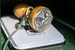 Stempel z drewnianą rączką i metalowym zabezpieczeniem na białej powierzchni.