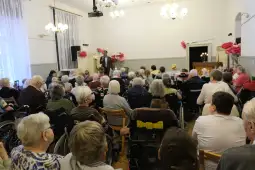 Spotkanie seniorów w sali z dekoracjami i wystąpieniem prelegenta.