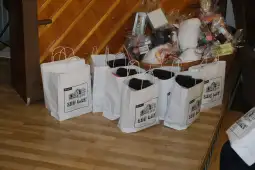 Białe torby papierowe z czarnymi detalami, obok kosz z różnymi przedmiotami.