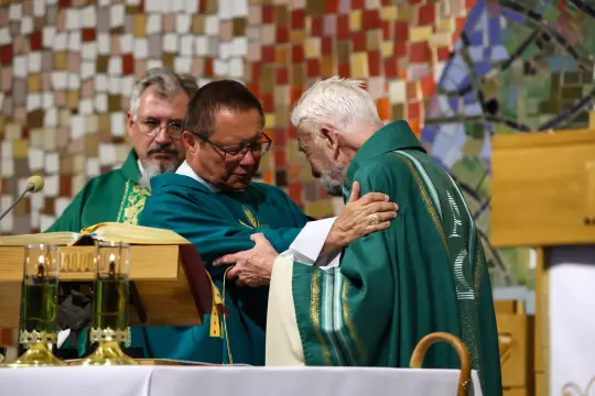 Dwóch mężczyzn w szatach liturgicznych podczas ceremonii religijnej.
