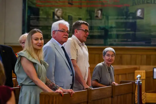 Cztery osoby stojące w sali sądowej, w tle widoczne tablice z informacjami.