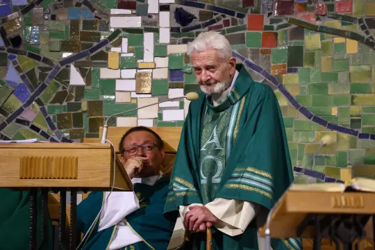 Kapłan w zielonej szacie liturgicznej przemawia do zgromadzenia.