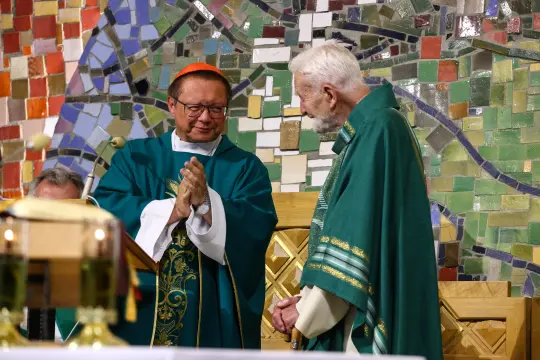 Duchowni w trakcie ceremonii religijnej w kolorowej scenerii mozaiki.