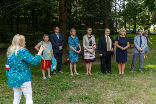 Grupa osób w formalnych strojach podczas wydarzenia na świeżym powietrzu.