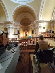 Osoba na wózku inwalidzkim w kościele, widok na wnętrze z ołtarzem i dekoracjami.