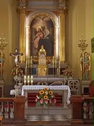Ołtarz z obrazem, świecami, kwiatami i figurami aniołów.