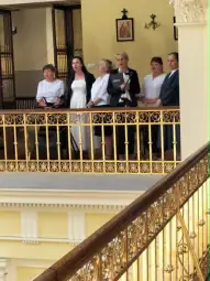 Grupa kobiet w eleganckich strojach na balkonie w budynku.