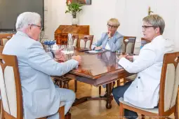 Spotkanie trzech osób przy stole w biurze, omawiają sprawy biznesowe.
