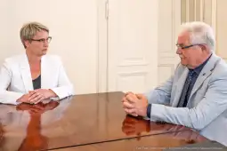 Dwie osoby siedzą przy stole w biurze, rozmawiając ze sobą.