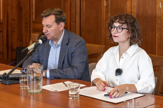 Mężczyzna i kobieta siedzą przy stole, prowadząc dyskusję podczas konferencji.