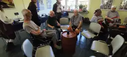 Grupa osób w strojach pirackich siedzi wokół beczki w pomieszczeniu.