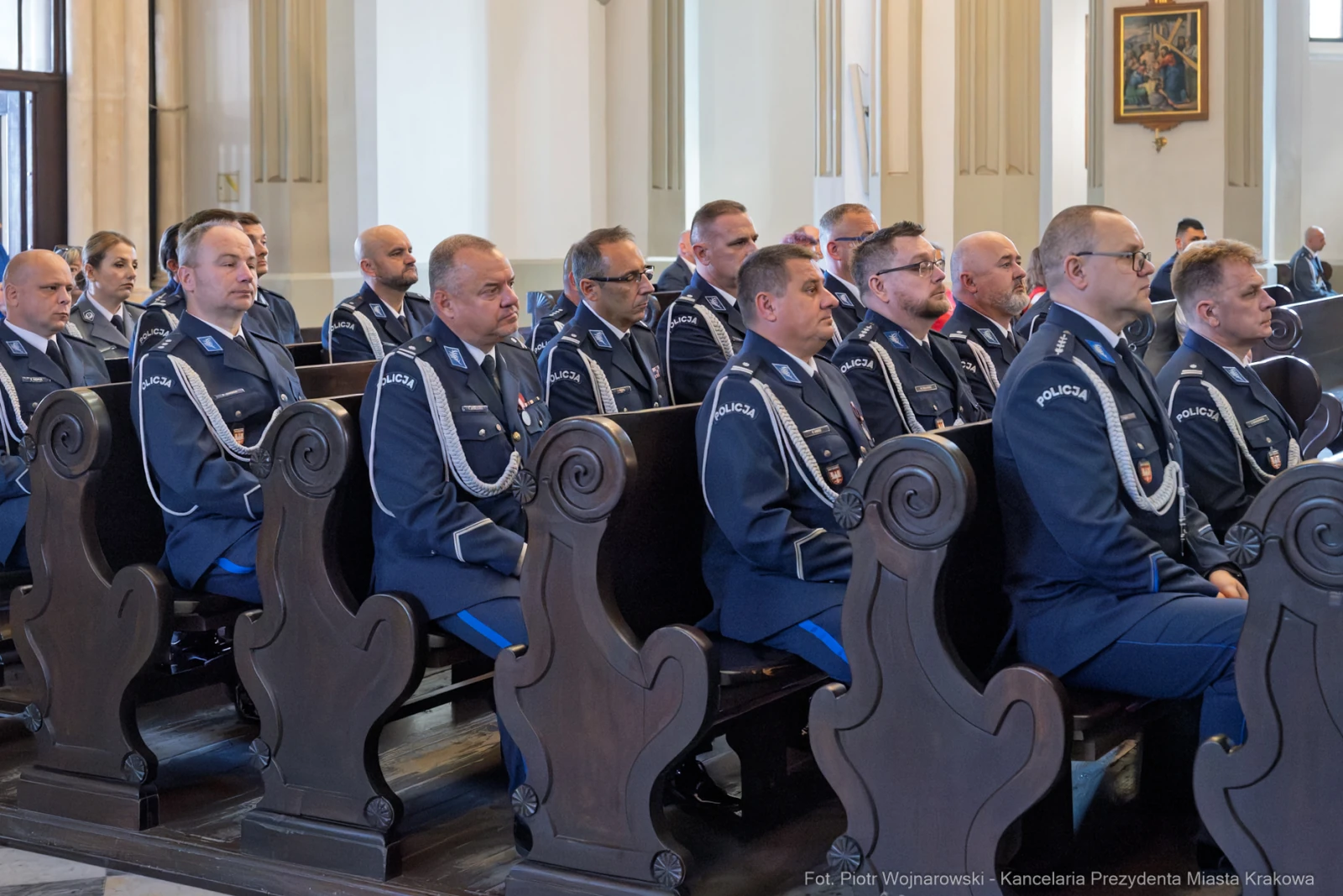 Uroczystość z udziałem mundurowych w sali z ławkami i dekoracjami.  Autor: Piotr Wojnarowski
