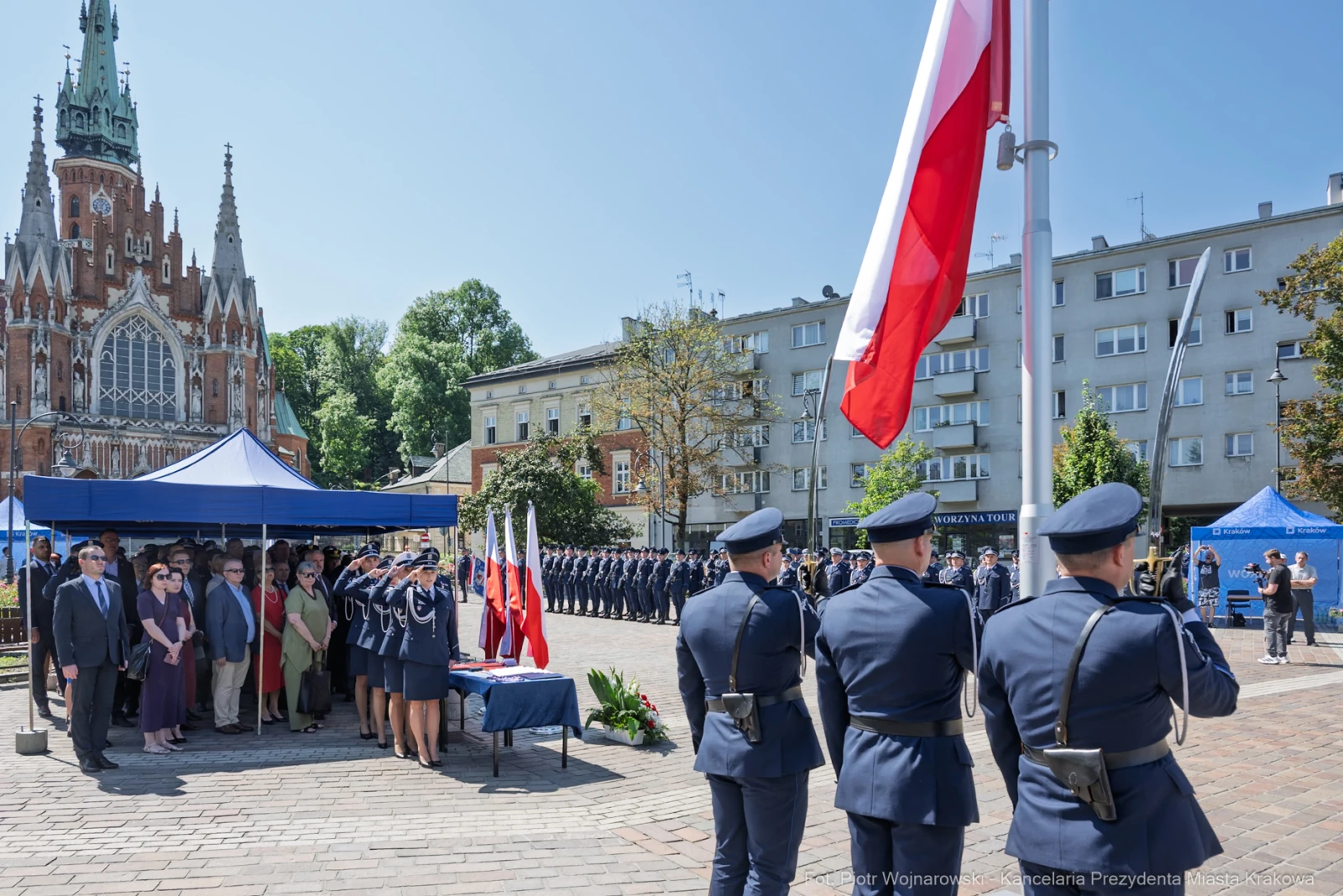 Uroczystość z udziałem mundurowych, flagi Polski i budynku w tle.  Autor: Piotr Wojnarowski