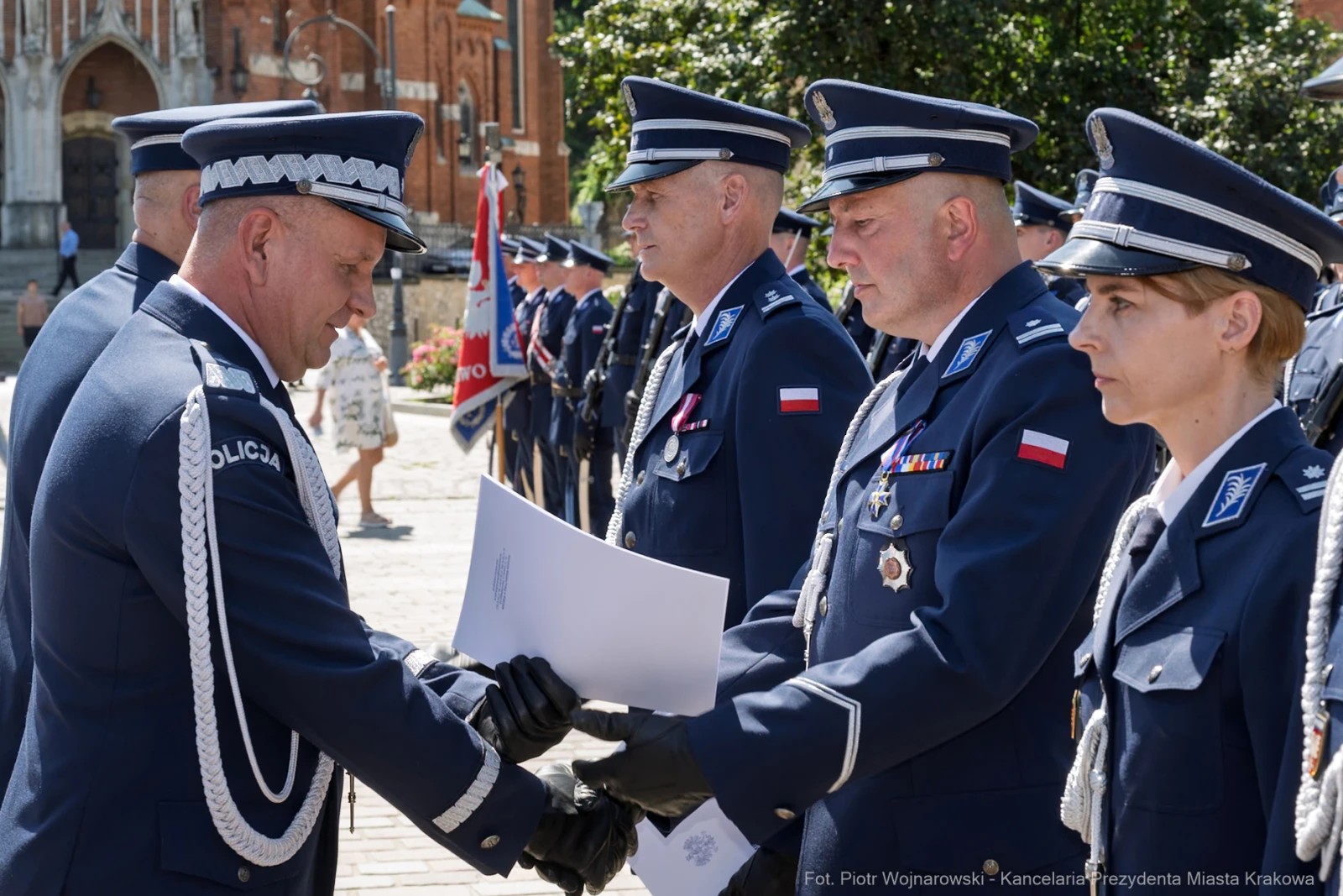Ceremonia wręczenia odznaczeń policjantom w mundurach na tle historycznej architektury.  Autor: Piotr Wojnarowski