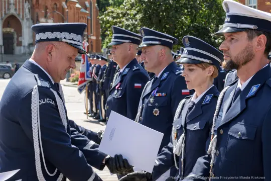 Ceremonia wręczenia odznaczeń policjantom w mundurach na tle budynków.