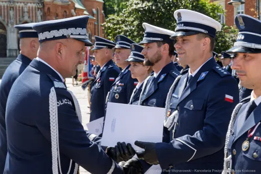 Ceremonia wręczenia odznaczeń policjantom w mundurach na tle budynku.