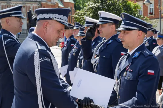 Ceremonia wręczenia odznaczeń policjantom w mundurach na tle budynków.