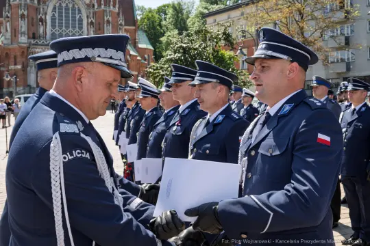 Ceremonia wręczenia odznaczeń policjantom w mundurach na tle budynków.