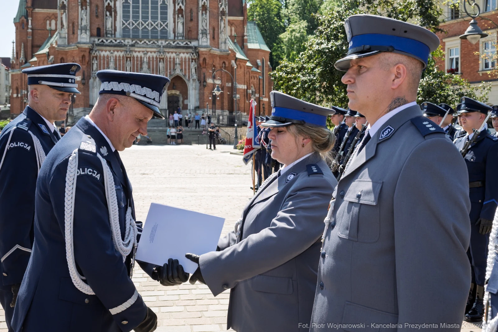 Ceremonia wręczenia odznaczeń policjantom przed budynkiem w tle.  Autor: Piotr Wojnarowski