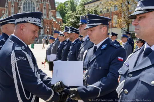 Ceremonia wręczenia odznaczeń policjantom w mundurach na tle zabytkowego budynku.