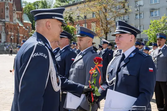Ceremonia wręczenia odznaczeń policjantom, mężczyźni w mundurach, kwiaty i dyplomy.